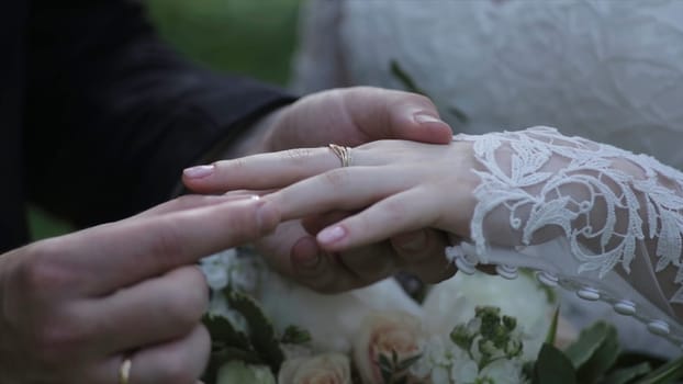 Bride wear ring on groom's finger. The groom puts the wedding ring to finger of the bride. marriage hands with rings. birde wears the ring on the finger of the groom HD