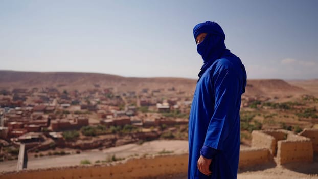 The Arab sheikh. Action. A man in national clothes against the background of deserts and small houses against the blue sky. High quality 4k footage