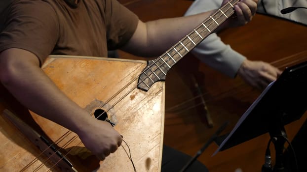 Balalaika wooden in the hands of the musician. Folk musical art of the rural traditional. Man plays the Balalaika-contrabass.