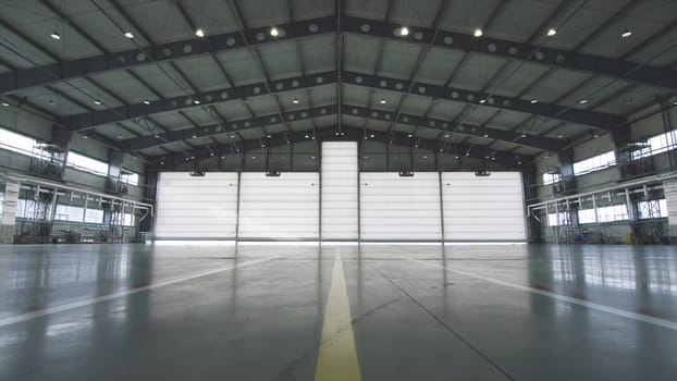 Roller shutter door and concrete floor inside factory building for industrial background. Airplane in front of half opened door to hangar. The open door of the hangar. Mechanic opening the door of a airplane hangar