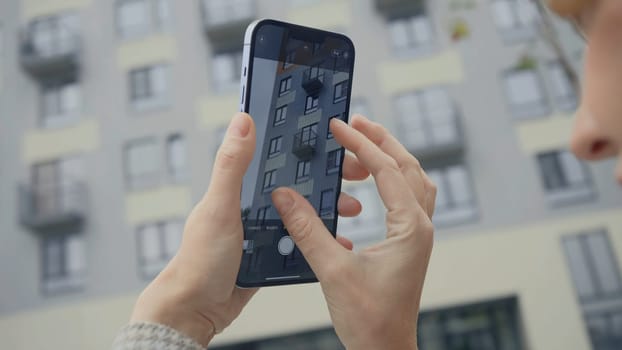 RUSSIA, MOSCOW - SEPTEMBER 27, 2021: Woman takes photos of building on phone. Action. Woman holds phone and takes pictures of building. New improved camera of iPhone 13.