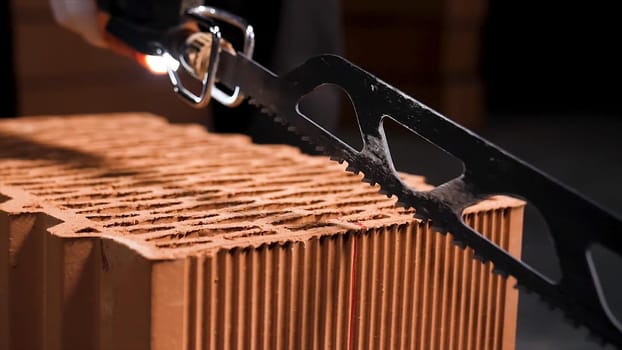Close up of electric cutting machine for small ceramic blocks turning on before cutting. Worker uses automatic saw to cut ceramic blocks.