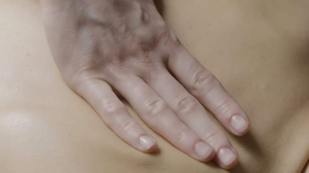 Spa treatments.Action.Gentle hands smeared with cream massage the back under towels. High quality 4k footage