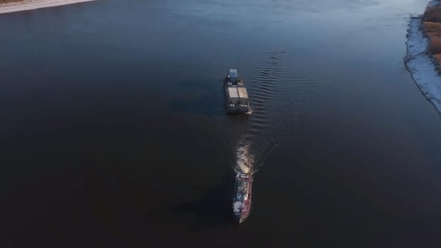 Top view of boat with cargo floating on river. Clip. Beautiful landscape with cargo boat floating on river. Cargo delivery by boat with trailer. Sea cargo transportation.