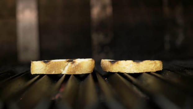 Close-up of two slices of bread grilled. Action. Fragrant simple bread slices fried in oven on grill. Toast on grill oven for perfect simple breakfast.