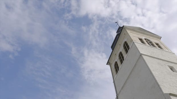 Church tower on a sunny day. Action. White Church steeple on background of blue sky.