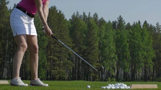 Golf player attempting the first stroke in the teeing area. Only legs of player to be seen.