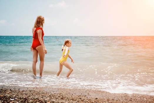 Happy loving family mother and daughter having fun together on the beach. Mum playing with her kid in holiday vacation next to the ocean - Family lifestyle and love concept.