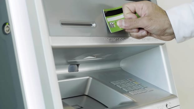 Male hand attaching card to the ATM bank machine for performing financial transactions. HDR. Close up of man entering bank card pin code