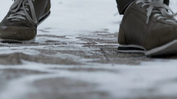 Close-up of male legs in winter shoes walking on snow. View of walking on snow with Snow shoes and Shoe spikes in winter. Men's legs in boots close up the snow-covered path in the winter forest.