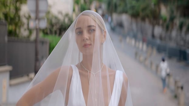 Portrait of a beautiful and attractive bride with blonde hair. Action. Close up of the face of a young woman in a wedding veil with make up