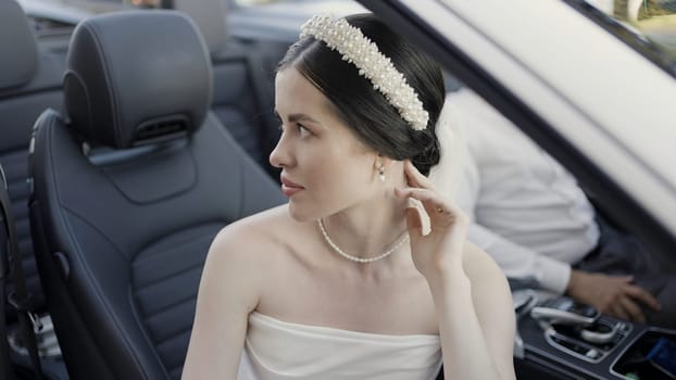 Bride and groom in wedding clothes sitting in cabriolet car. Action. Man and woman in luxury car