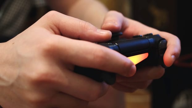 Close-up of man's hands holding a remote control from a game console and playing video games. Weekends and recreation