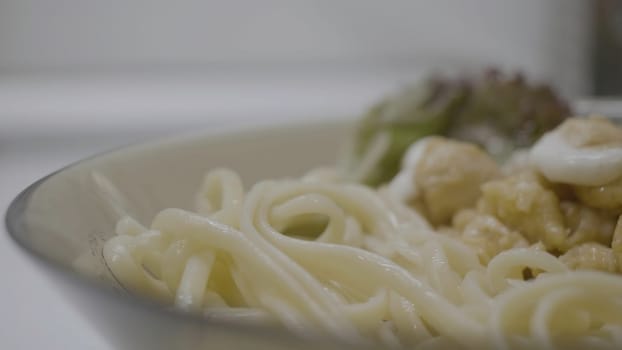 Fettuccine Alfredo with white chicken zucchini sauce. Pasta fettuccine alfredo with chicken, parmesan and parsley on white background close up. Italian cuisine 4K