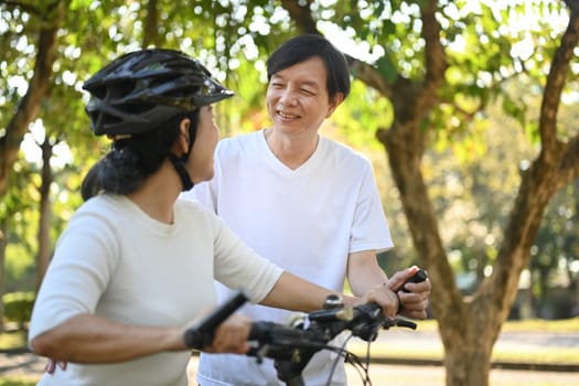 Happy senior couple enjoying riding bicycles in summer park. Retirement and healthy lifestyle