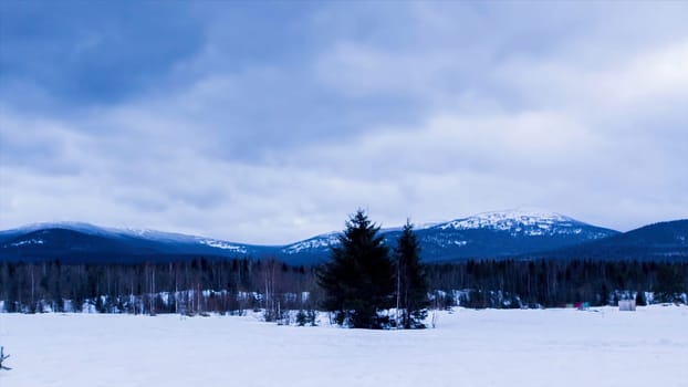Highroad,snow mountain and blue sky with white cloud under the winter sunlight. Mountainous snow-covered terrain. Timelapse.