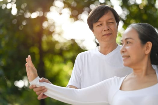 Shot of active middle aged couple practicing posture during Tai Chi class in the park