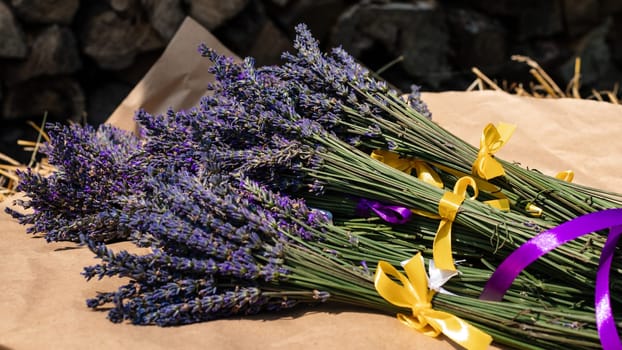 Lavender bouquets with purple and yellow ribbons lie on kraft paper