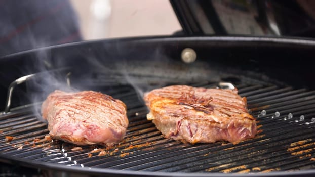 Beef steaks on the grill with flames. Cooking steaks on the coals. Concept of eating meat.