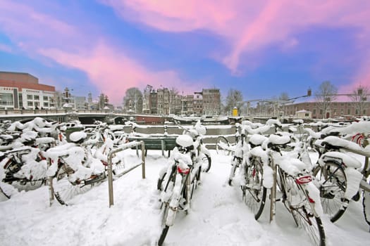 Snowy city Amsterdam in the Netherlands in winter at sunset