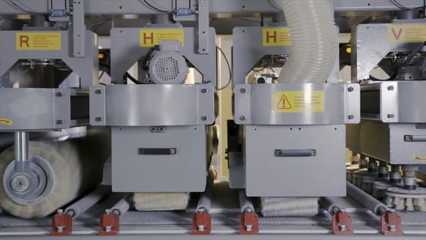 Industrial machines with rotating bristles. Action. Rotating bristly nozzles of different sizes read and paint wooden boards in industrial enterprise.