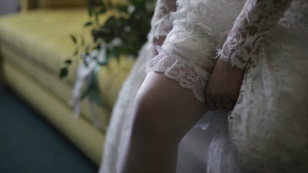 Bride dresses stockings on feet. Beauty bride in a dress wearing stockings wedding indoors. Female portrait nice lady in a dress. Closeup of woman hands HD