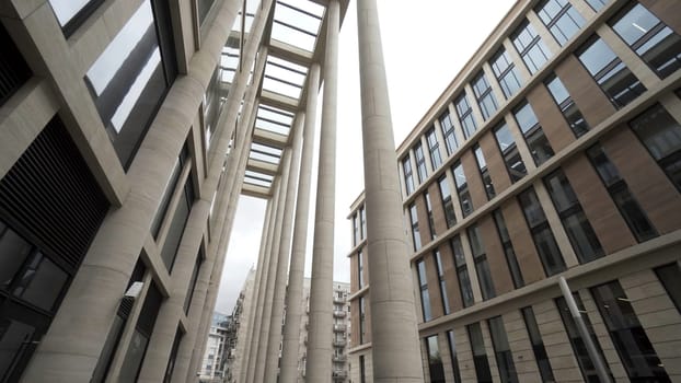 Facade of a building with marble columns. Bottom view of a modern architectural complex, new building with light beige pillars and larg windows.