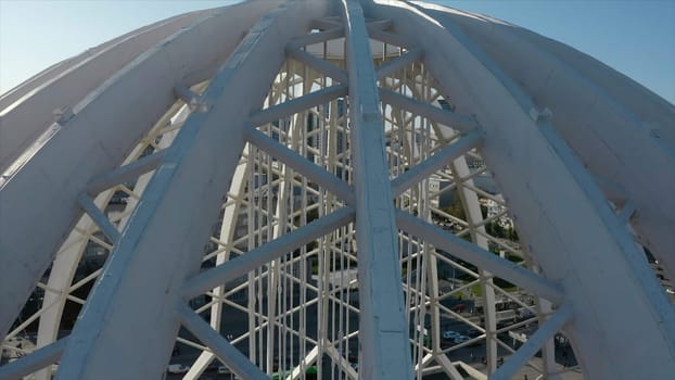 Top view of domed structure with beams. Stock footage. Beautiful architecture of metal dome with beams. Dome made of metal semi-arches with air space on background of modern city.