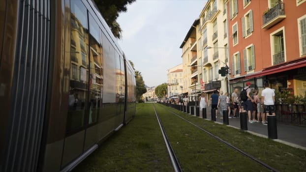France, Paris - June, 2019: Modern trams riding along rails. Action. Modern stylish models of trams do not need wires. New trams ride on rails of european city with walking tourists.