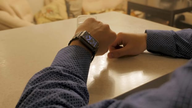 Handsome stylish male managing time on electronic watch. Young man checking modern wrist clock.