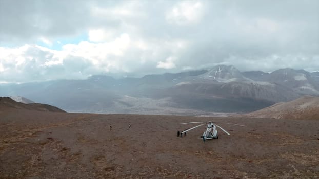 Top view of helicopter standing on mountain. Clip. Helicopter stopped on mountain with view of horizon with clouds. Beautiful landscape with mountains and sun rays in cloudy clouds.