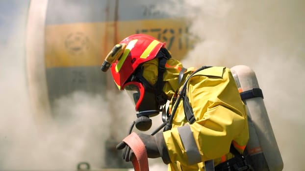 Male firefighter in the helmets and uniform with smoke on the background. Clip. Fireman preparing fire hose, emergency concept