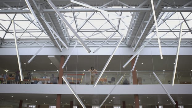 RUSSIA, YEKATERINBURG - MARCH 17, 2022: Glass ceiling and three-story market. ART. The camera looks down. A large light glass ceiling is shown, and under it people walk and buy things.