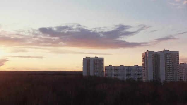 Time lapse effect for amazing clouds and sunset in the sky above the houses. Modern urban architecture, residential high rise buildings located in the sleeping area of the city with autumn trees.