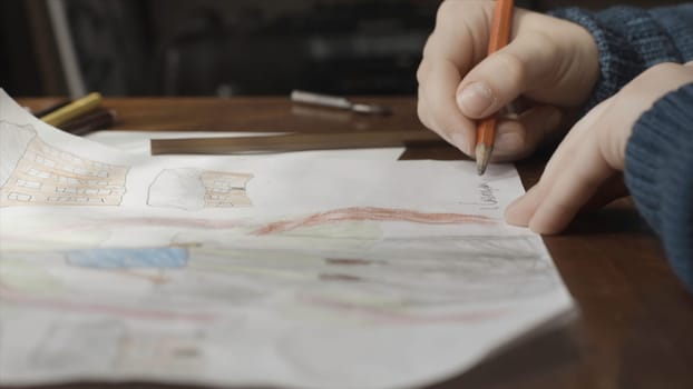 Close up of a boy doing his homework and studying at home. A boy draws at the table. Education concept.