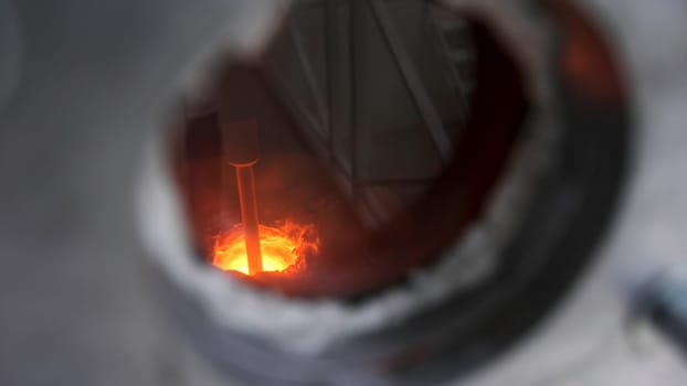 Close up of small window inside metal barrier for observing melting process, modern technologies concept. Melting furnace during working process.
