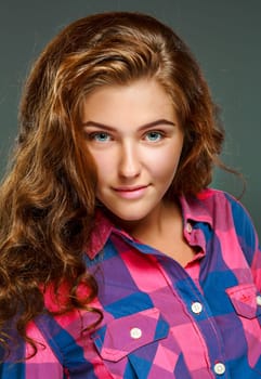 Portrait beautiful young brunette woman with wavy hair, looking at the camera, isolated on dark background