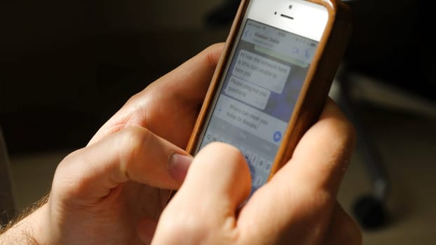 Man sending or reading sms on his mobile phone. Closeup of man typing a message on mobile phone. The man writes on his smartphone using two hand.