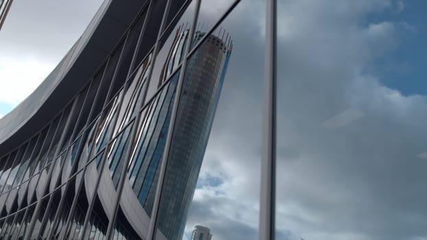 Reflection of high-rise in glass building. Stock footage. Beautiful modern architecture of glass buildings. Reflection in the windows of glass building.