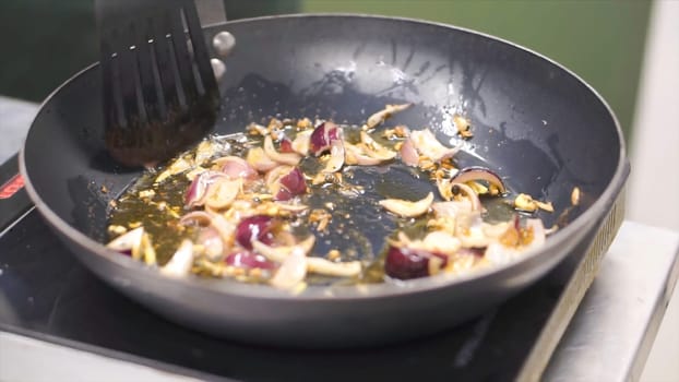 Fried onion in oil in a frying pan. Clip. Vegetarian stir fry. Healthy eating. Top view. Top view stir fry vegetables in a wok, on the stove.