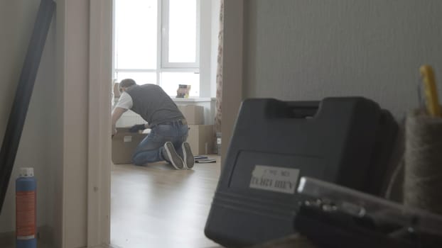 Man is looking for something in a box, general view.