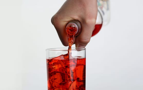 Man pouring orange drink into glass with ice closeup. Nonalcoholic cocktails concept