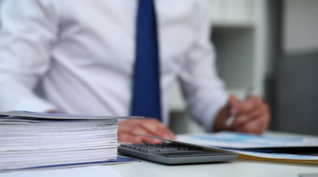 White binder lie at worktable with male clerk worker in background closeup. Revision help internal revenue service agent investigation bank database workflow