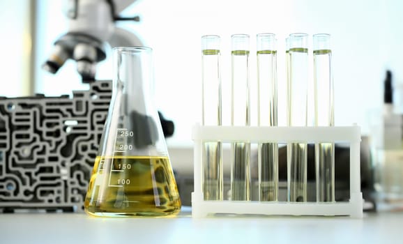 Test tube chemistry flask against background of hydroblock acp with yellow liquid purified oil from recycling and lubricating materials sale closeup