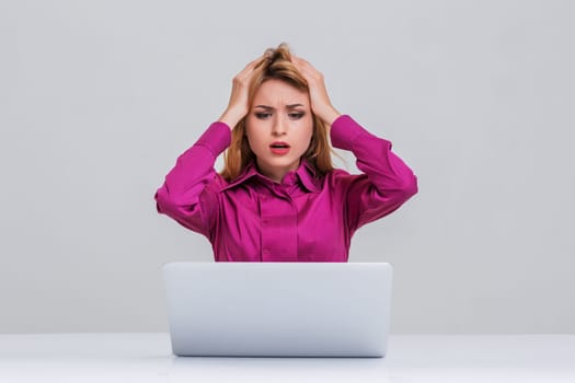 Young businesswoman working at laptop computer. she is going through. her head in her hands