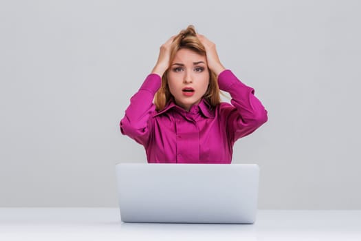 Young businesswoman working at laptop computer. she is going through. her head in her hands