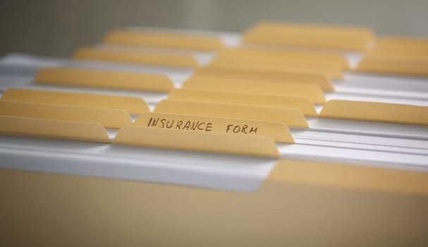 Yellow folders with labels and paper in a row in the insurance file closeup