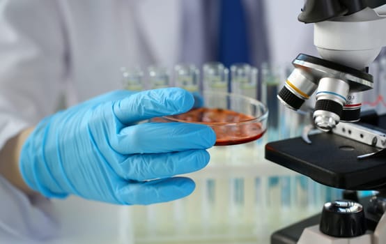 Male chemist holds test tube of glass in hand mold overflows liquid solution potassium permanganate conducts an analysis reaction takes various versions of reagents using chemical manufacturing.