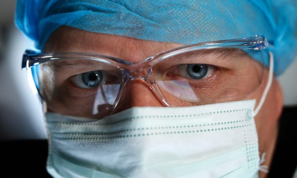 Handsome male physician face wearing protective mask and glasses closeup. Save patient life emergency help sterile bioclean physical exam vet doc dentist 911 job concept