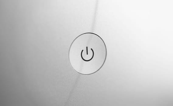 Silver coarse turn on and off button at gray blank back panel of electronic gadget closeup